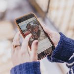 Person creating and posting an Instagram Reel using a smartphone indoors with editing tools visible on screen
