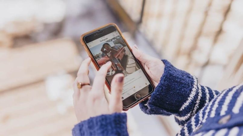 Person creating and posting an Instagram Reel using a smartphone indoors with editing tools visible on screen