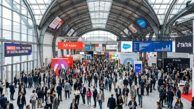 Thousands of digital marketing professionals filling the exhibition floor at DMEXCO 2026 in the Koelnmesse, Cologne, Germany, with branded booths and digital screens visible throughout the hall