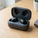 Pair of sleek black wireless earbuds sitting inside an open charging case on a desk.