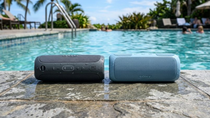 Two waterproof Bluetooth speakers sitting on wet poolside deck for audio comparison.