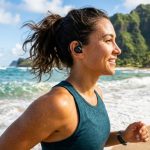Person wearing waterproof earbuds while jogging on a sunny Hawaiian beach.